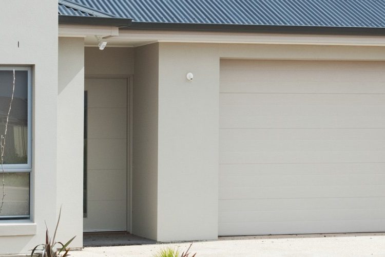 Stock photograph of a house finished in monolithic plaster cladding with a dark metal roof and a double garage door